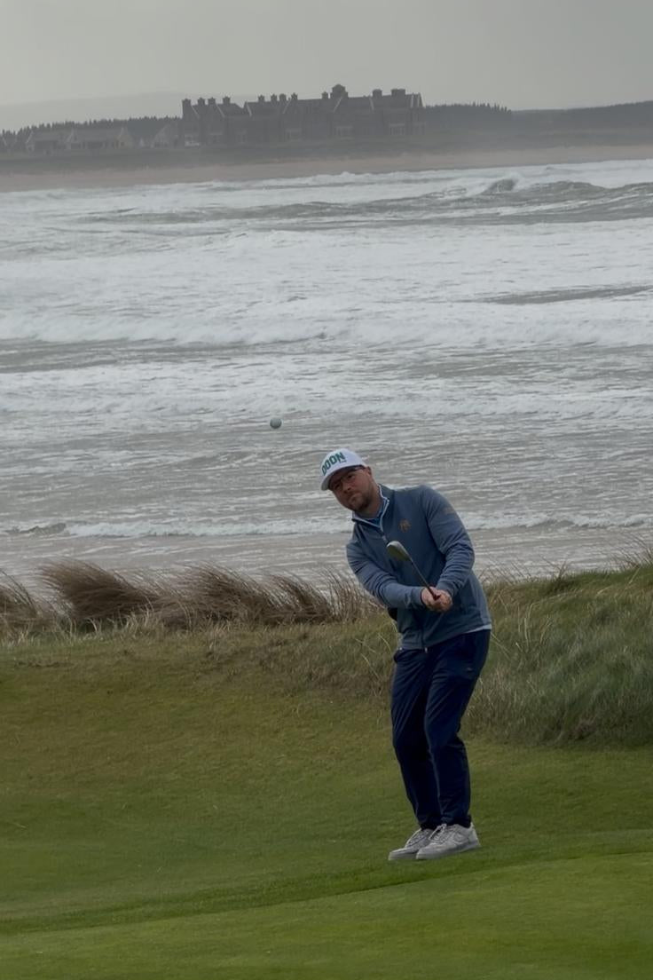 Person playing golf on a grassy area near a body of water